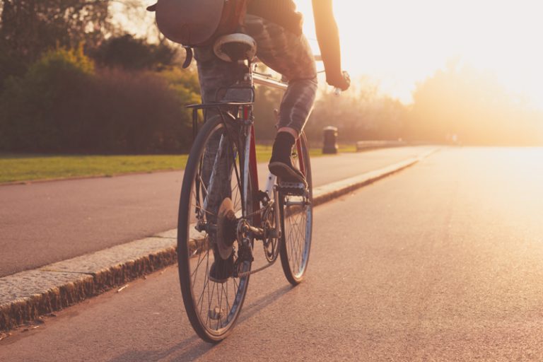 persona montando en bici por el asfalto con puesta de sol