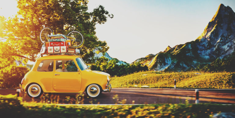 mini coche amarillo con maletas rojas encima en el campo paisaje bonito prado con puesta de sol primavera
