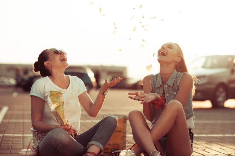 mujeres chicas amigas disfrutando comiendo patatas fritas al aire libre en un parking de coches